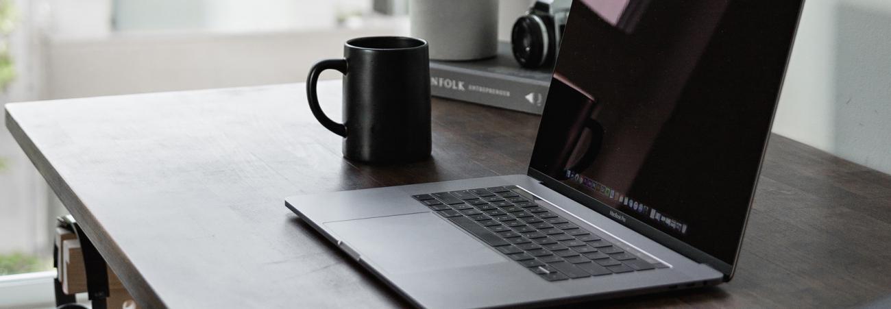 Ordinateur portable vu de 3 quarts avec tasse de café à sa gauche